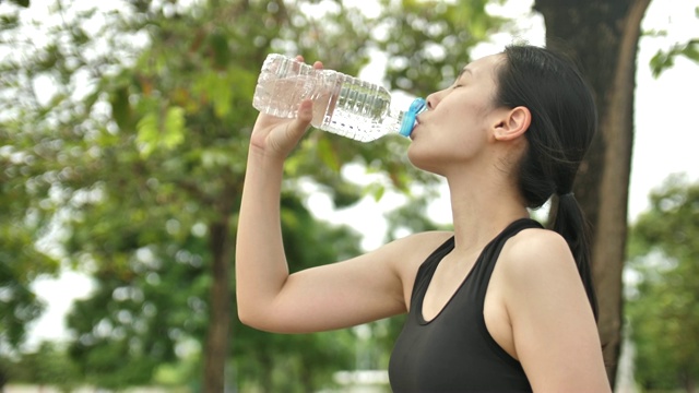 亚洲健身妇女在跑步后喝水视频素材