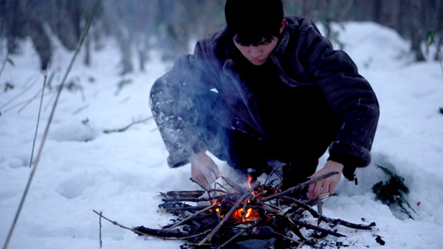 人在冬天下雪的森林里生火视频素材