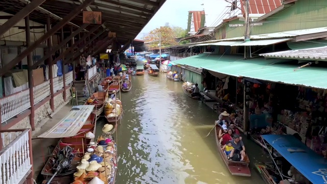 泰国Ratchaburi，日落时分，运河边的Damnoen Saduak水上市场和传统风格的商店，还有观光船。视频素材