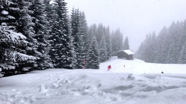 大雪在山上以森林和传统的木屋为背景视频下载