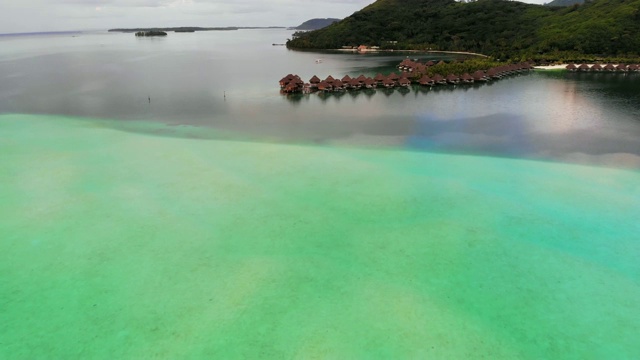 空中向前:位于波拉波拉岛大理石绿色和蓝色海洋中的热带小屋，法属波利尼西亚视频素材