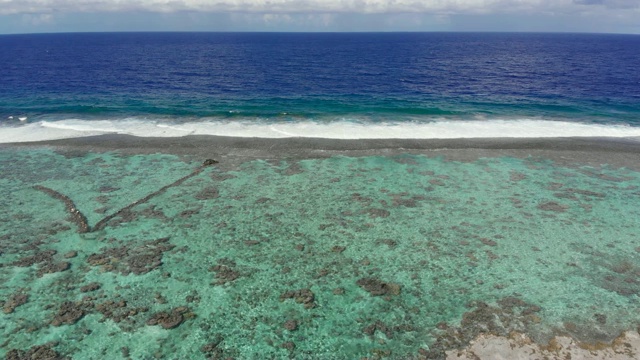 空中下降:在法属波利尼西亚，充满活力的蓝色热带海浪撞击浅滩视频素材