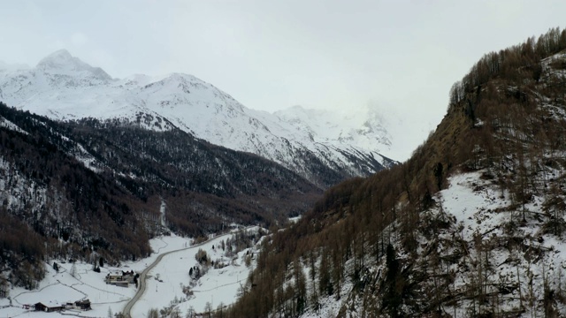 航拍:意大利南蒂罗尔松林雪山间美丽山谷中的房屋视频素材