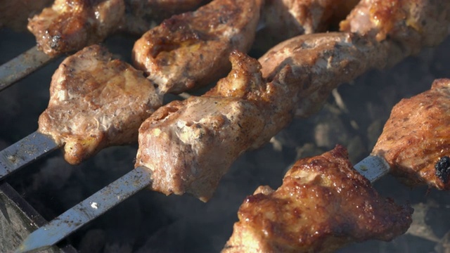 开胃多汁的猪肉串在木炭烤架上用金属串烹饪，带有烟视频素材