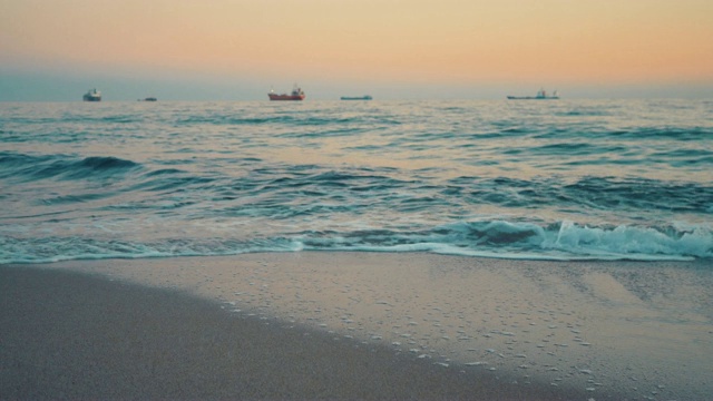 湛蓝的海面上明亮的黎明。海岸。水面上的小波浪。大型商业货船出现在地平线上。Copyspace视频素材