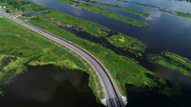 汽车在蓝色湖泊之间的高速公路上行驶视频素材