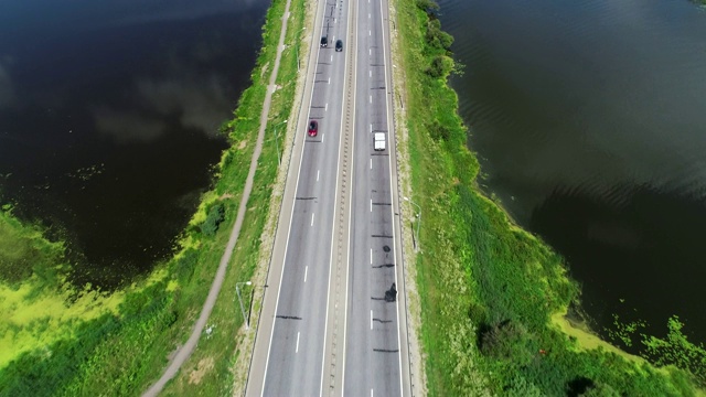 汽车在蓝色湖泊之间的高速公路上行驶视频素材