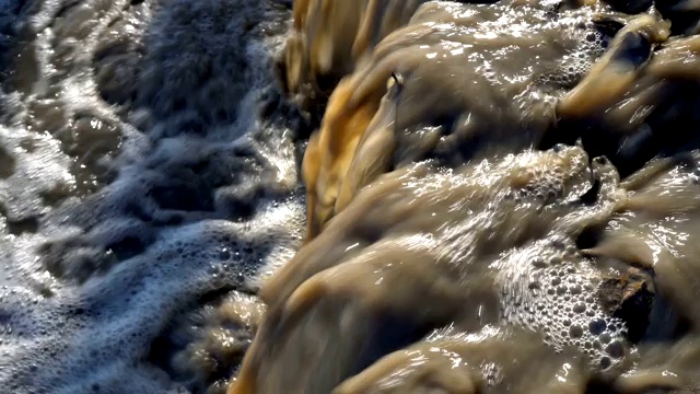 肮脏的废水流进河里。肮脏、浑浊的水流特写。环境污染。4 k。25 fps。视频素材