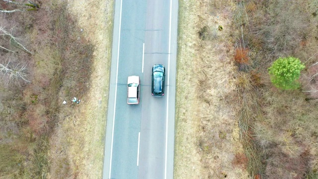 鸟瞰图的黑色汽车行驶在乡村道路在森林。无人机在松树林的砾石路上飞行视频素材