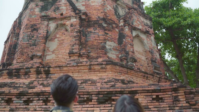 旅行者亚洲夫妇在泰国大城府度假，背包客甜蜜的夫妇享受他们的旅程在传统城市惊人的地标。生活方式情侣旅游度假概念。视频素材