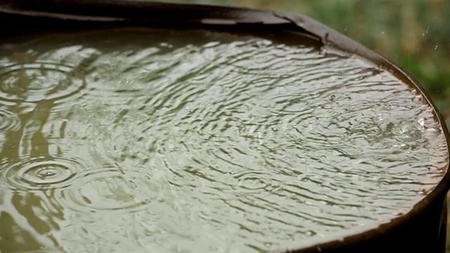 雨水流入生锈的旧桶里。雨滴特写镜头。视频素材