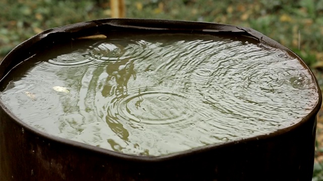 雨水流入生锈的旧桶里。雨滴特写镜头。视频素材