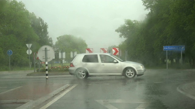 汽车在城市道路上环行，雨落。恶劣的天气条件。4 k视频素材