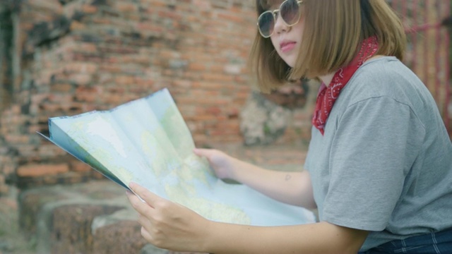 旅行者亚洲女人的方向和看位置地图，而在泰国大城府度假旅行，背包女享受旅程在传统的城市。生活方式女性旅游概念。视频素材