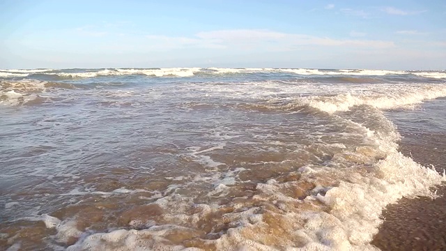 相机在波浪上的移动。海浪靠近海岸，阳光在水中照耀。风景如画的白沙海岸冲刷着海浪。背景或纹理视频素材