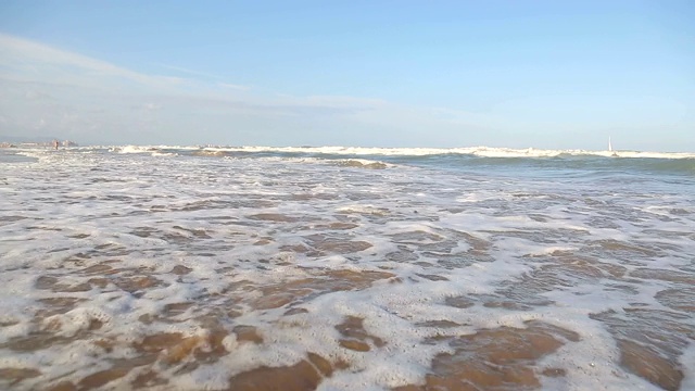 相机在波浪上的移动。海浪靠近海岸，阳光在水中照耀。风景如画的白沙海岸冲刷着海浪。背景或纹理视频素材