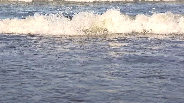 海浪靠近海岸，阳光在水中照耀。风景如画的白沙海岸冲刷着海浪。背景或纹理视频素材