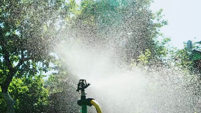 一个专业的自动灌溉系统以小水滴的形式在夏季的农村地区的场地上喷洒水。视频素材