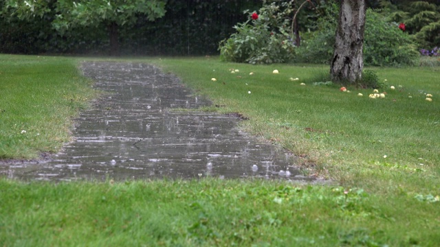 大雨水滴落在花园的石头路面上，在雨天溅起水花。4 k视频素材