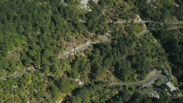 鸟瞰图山形蜿蜒的道路与卡车和汽车。股票。道路交通蜿蜒在高山狭窄的角落，汽车变成绿色的森林视频素材