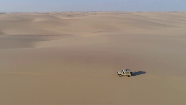 4K平移鸟瞰图的4x4车辆驾驶在骷髅海岸沙丘，纳米比亚沙漠视频素材