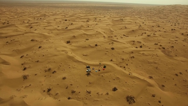 空中平移拍摄在无尽的沙漠中一个小型越野营地视频素材