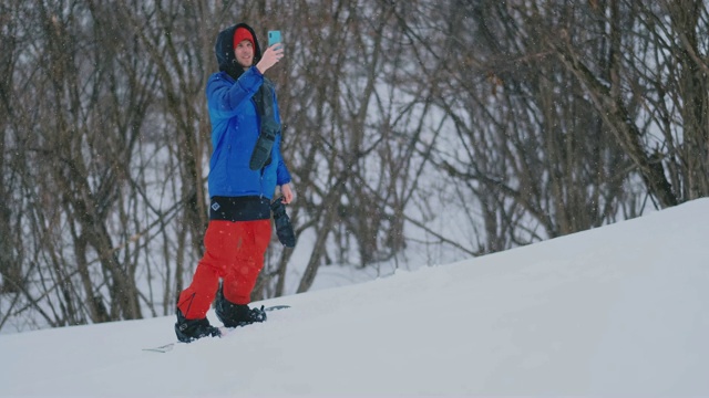 一名滑雪者在滑雪坡上驾驶时使用智能手机的慢动作镜头视频素材