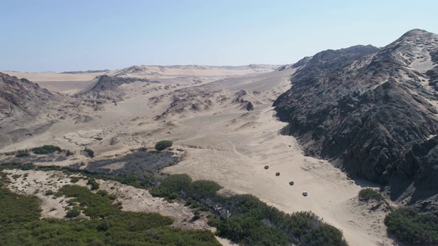 4K高鸟瞰图的车队4x4车辆之间的沙丘和山脉之间的骨骼海岸，纳米比亚沙漠，纳米比亚视频素材