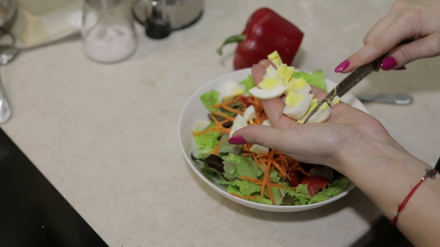 女性用手切了一个鸡蛋，拌上了红灯笼椒和生菜沙拉视频素材