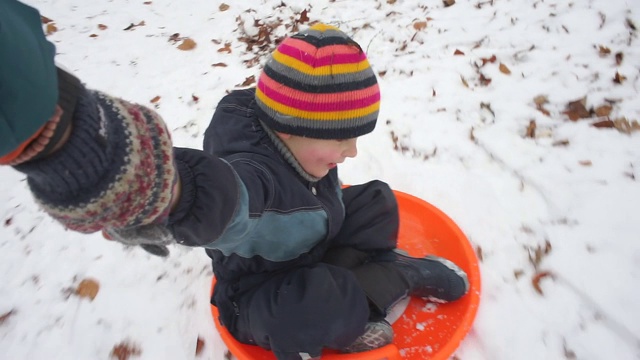 孩子和爸爸在雪地里坐雪橇视频素材