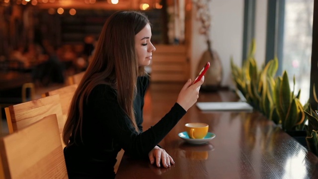 坐在咖啡馆里为她的社交账号拍摄一杯咖啡的女子博主视频素材