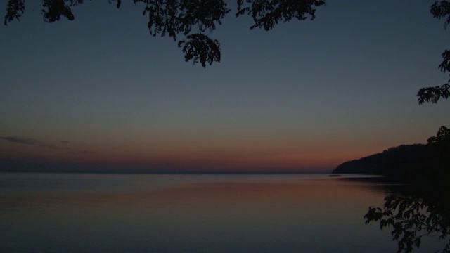 日出时美丽的湖泊或河流，前景中有一根树枝视频下载