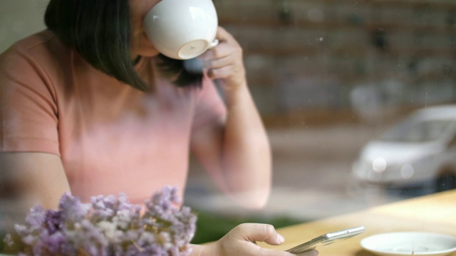 女人用智能手机在咖啡馆喝咖啡，慢镜头视频素材