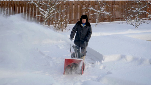 冬天，一个男人在清理院子里的雪堆视频素材