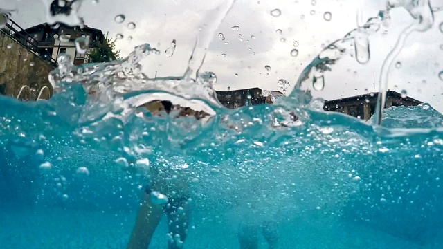 两个快乐的女孩微笑着享受在游泳池在下雨的天气，gopro圆顶半水下视图，慢动作视频素材