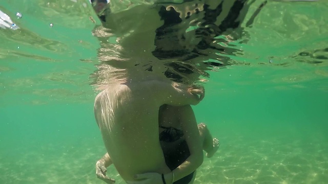 欢快的情侣在海洋中游泳，浪漫的拥抱和触摸，gopro圆顶半水下视图，慢镜头视频素材