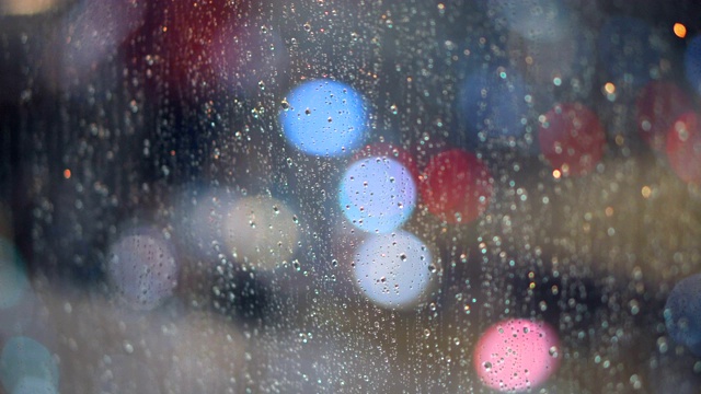 关闭雨在窗户在夜晚与散景灯的背景视频素材