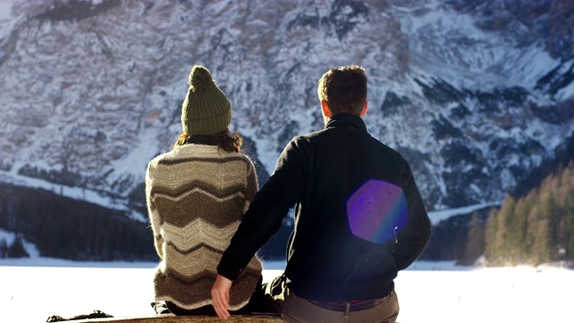 一个女孩休息放松，看着眼前的雪山与男友拥抱，情侣们在雪地里散步后拥抱。视频素材