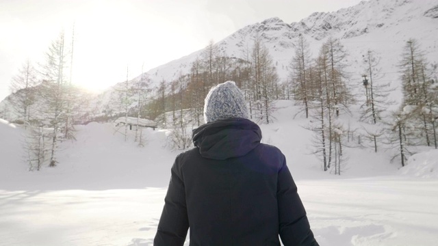 在冬天的一天，一个美丽的女人在山上玩雪，呼吸着清新的空气，沉浸在大自然中。视频素材