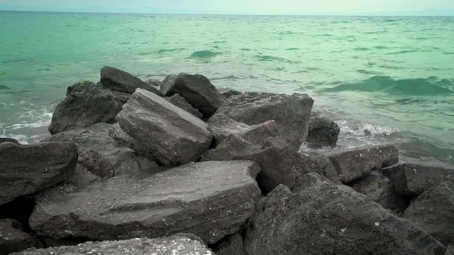 海浪拍打着多石的海滩，形成水花，慢动作视频素材