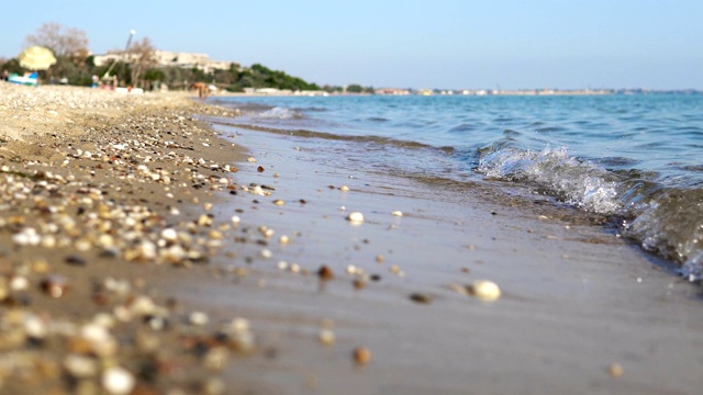 夏季概念背景，海边有平静的海浪拍打着海滩上的沙子和卵石，电影的dof视频素材