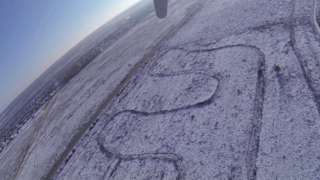 一架悬挂式滑翔机在冬天白雪覆盖的草地和森林上空起飞。视频下载