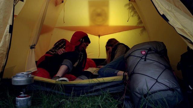 露营活动。夫妇俩在帐篷里查看地图视频素材