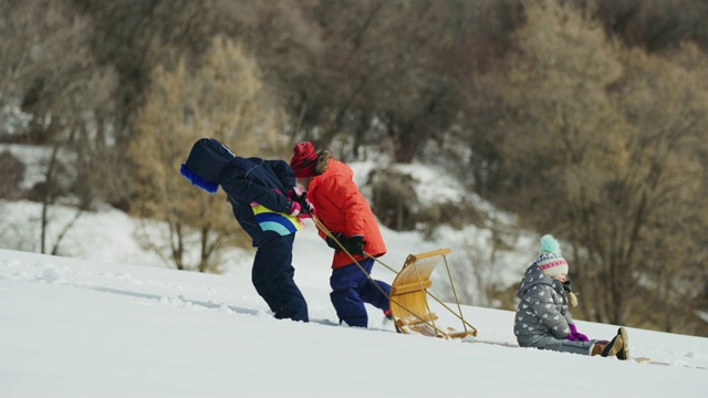 美国犹他州南福克，孩子们在冬天拉着雪橇上山，然后停下来的跟踪镜头视频素材