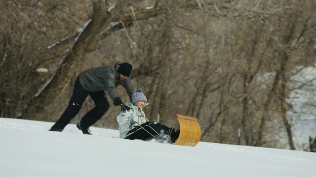 美国犹他州南福克，一名男子推着一名女子滑雪橇下坡视频素材