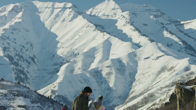 美国犹他州南福克山附近，倾斜到家人跪在雪中堆雪人视频素材