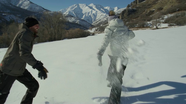 美国犹他州南福克山附近，一名男子在雪地里追逐和拦截一名女子的慢动作跟踪镜头视频素材