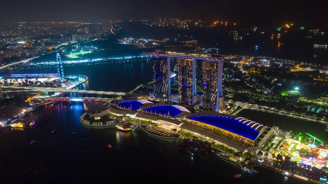 夜色照亮了新加坡城市，著名的酒店海湾上空显示了4k时间跨度的航拍全景视频素材