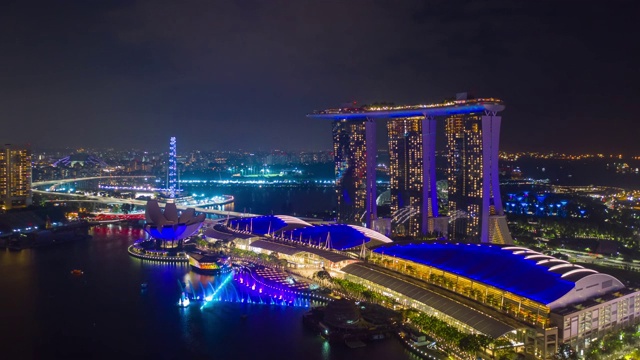 夜色照亮了新加坡城市，著名的酒店海湾上空显示了4k时间跨度的航拍全景视频素材