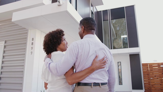 Middle aged black couple stand outside admiring their modern home, close up,Ê back view视频素材